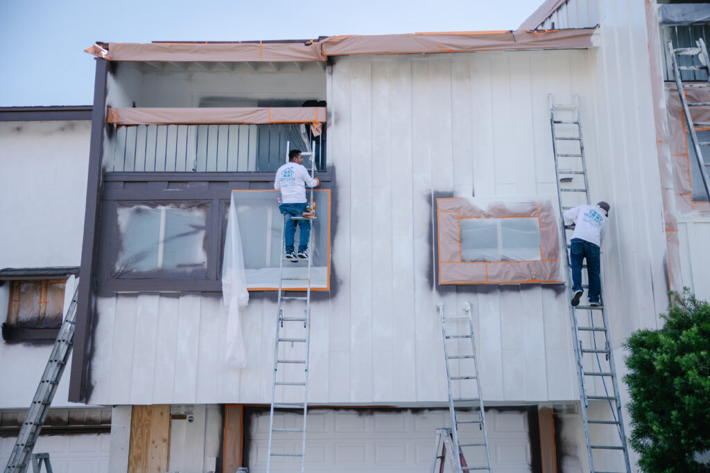 two men painting outside or building